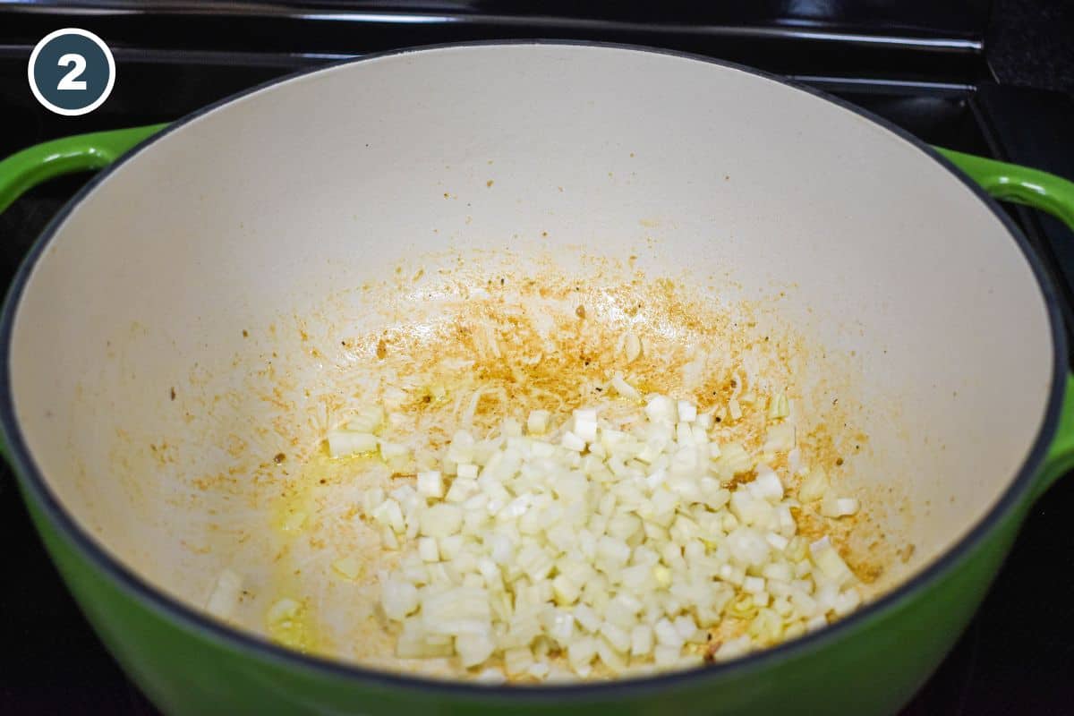 Diced onions cooking in the pot with browned bits on the bottom.
