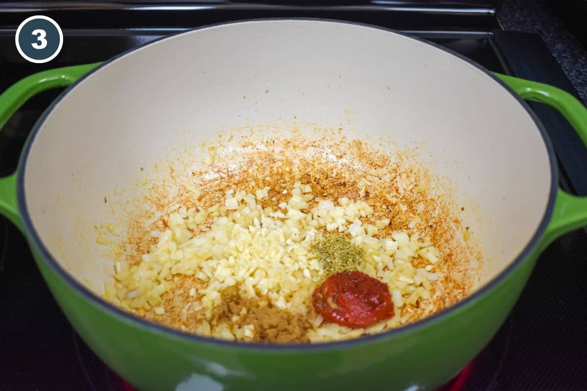 Garlic, tomato paste, cumin, and oregano added to the sautéed onions.