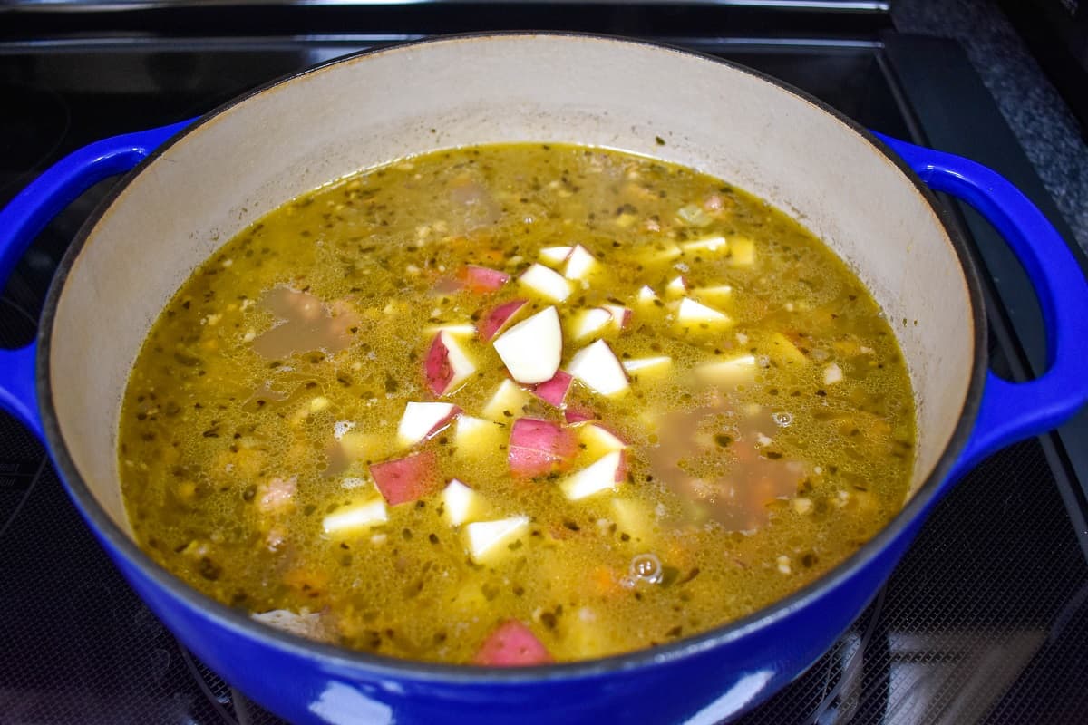 Cut red potatoes in the broth with the other ingredients in a large, blue pot.