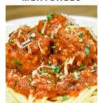 Italian sausage meatballs in a tomato sauce, served on a bed of spaghetti and garnished with chopped parsley and grated Parmesan cheese.