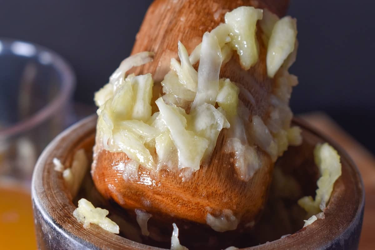 Smashed garlic on a pestle.