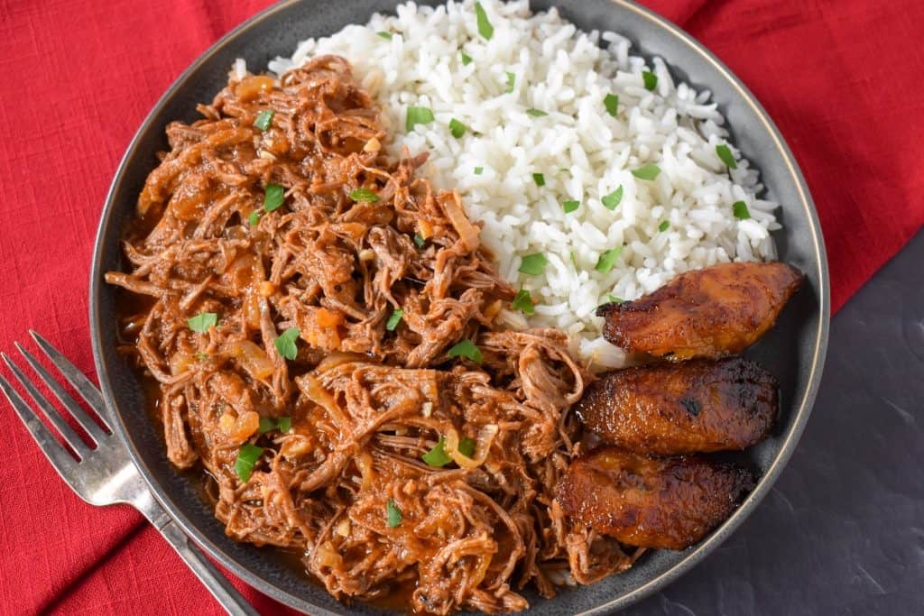 The finished ropa vieja served with white rice and fried sweet plantains on the side.