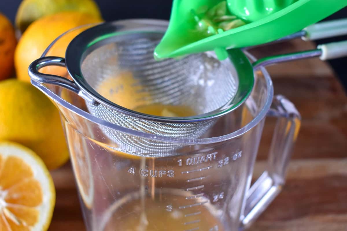 Straining sour orange juice in a mesh strainer.