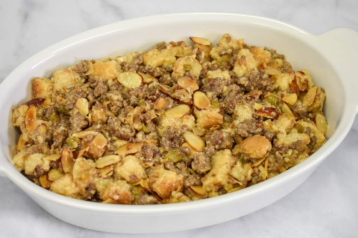 The stuffing in a white casserole dish set on a white table before baking.