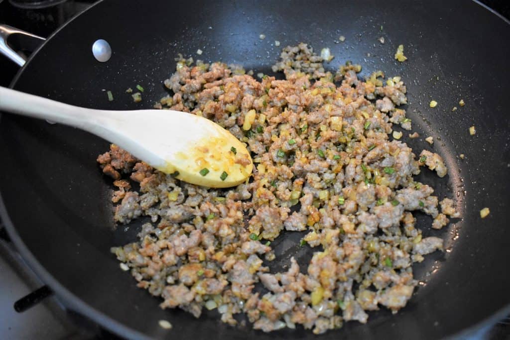 Sausage, onions, sage and spices browning in a large black skillet.