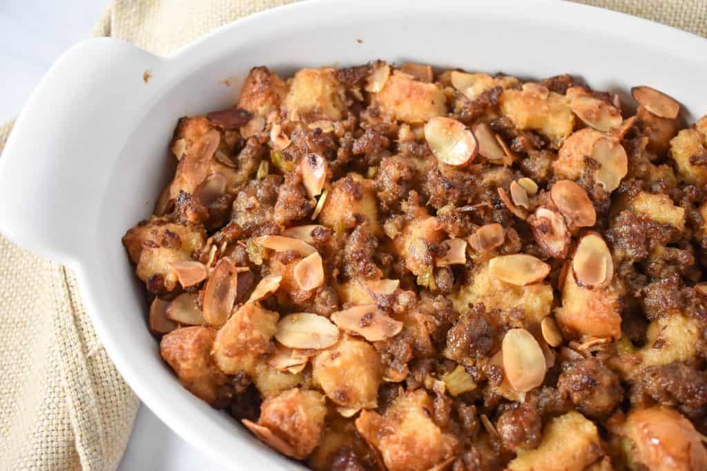 Sausage stuffing in a white casserole dish with a beige linen on the side.