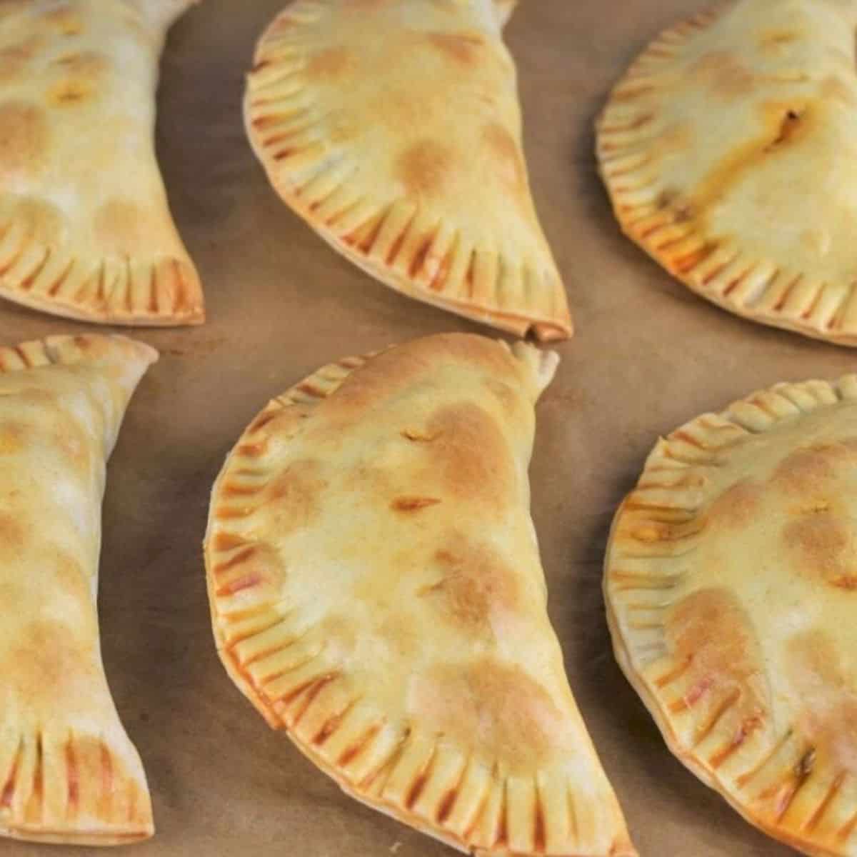 Baked Beef Empanadas arranged on a parchment paper lined baking sheet.