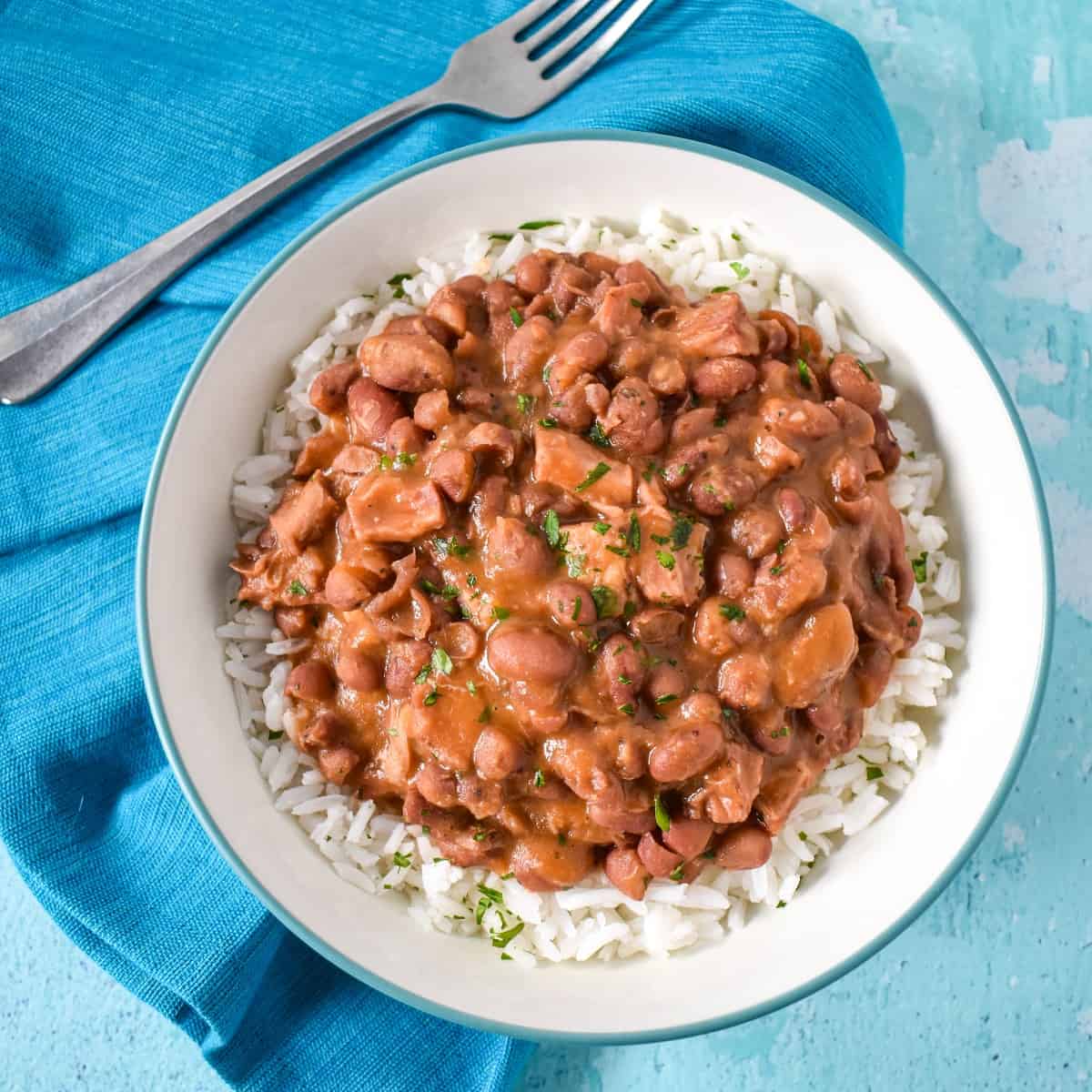 The Cuban-style red beans served over white rice in a white bowl set on an aqua linen.
