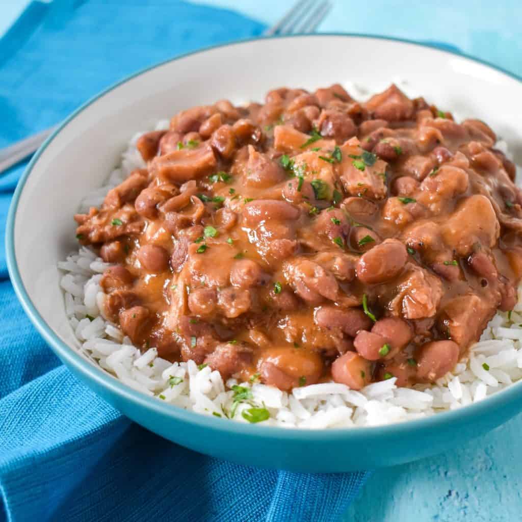 The Cuban-style red beans served over white rice served in a white bowl set on an aqua linen.