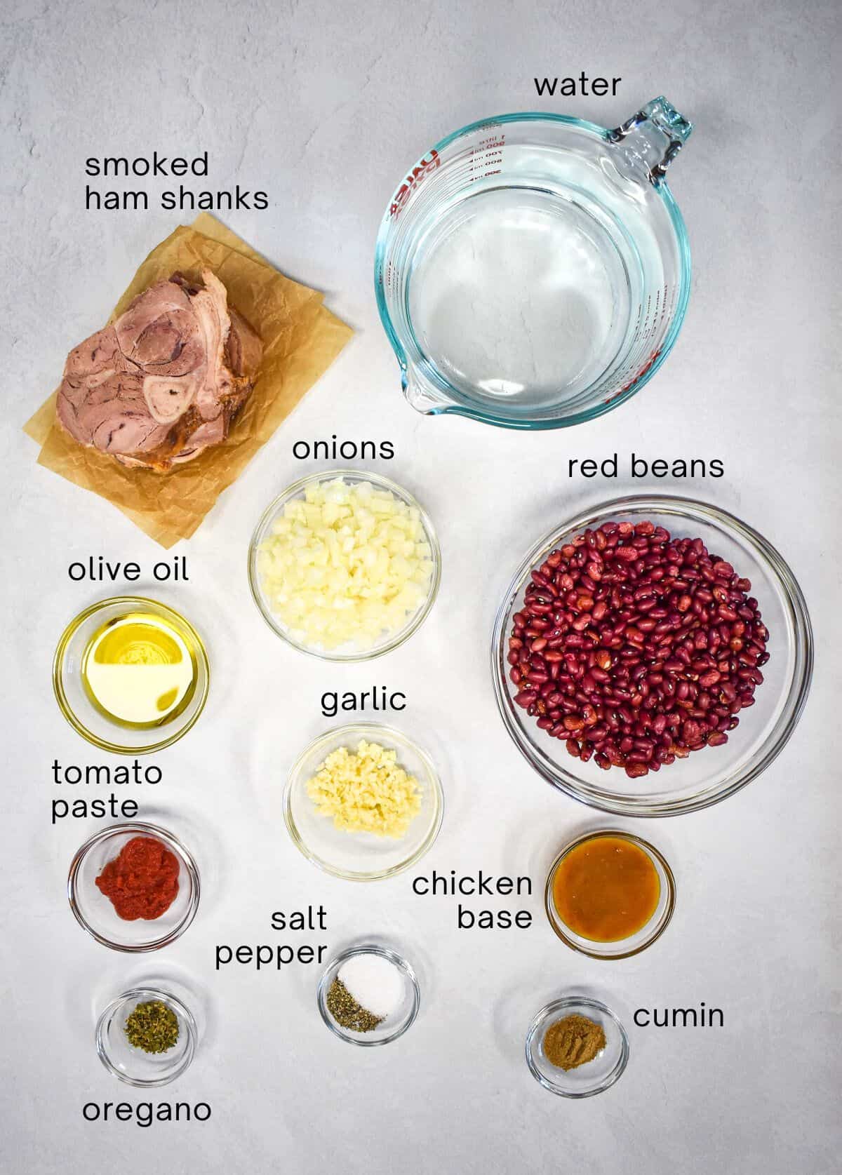 The ingredients for the red beans arranged in glass bowls on a white table with each one labeled in small black letters.