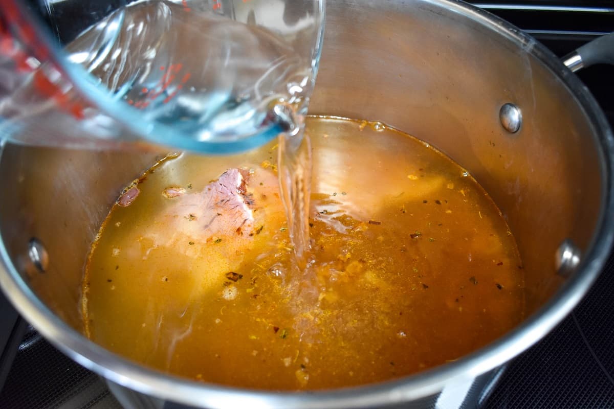 Water being added to the ingredients in a large pot.