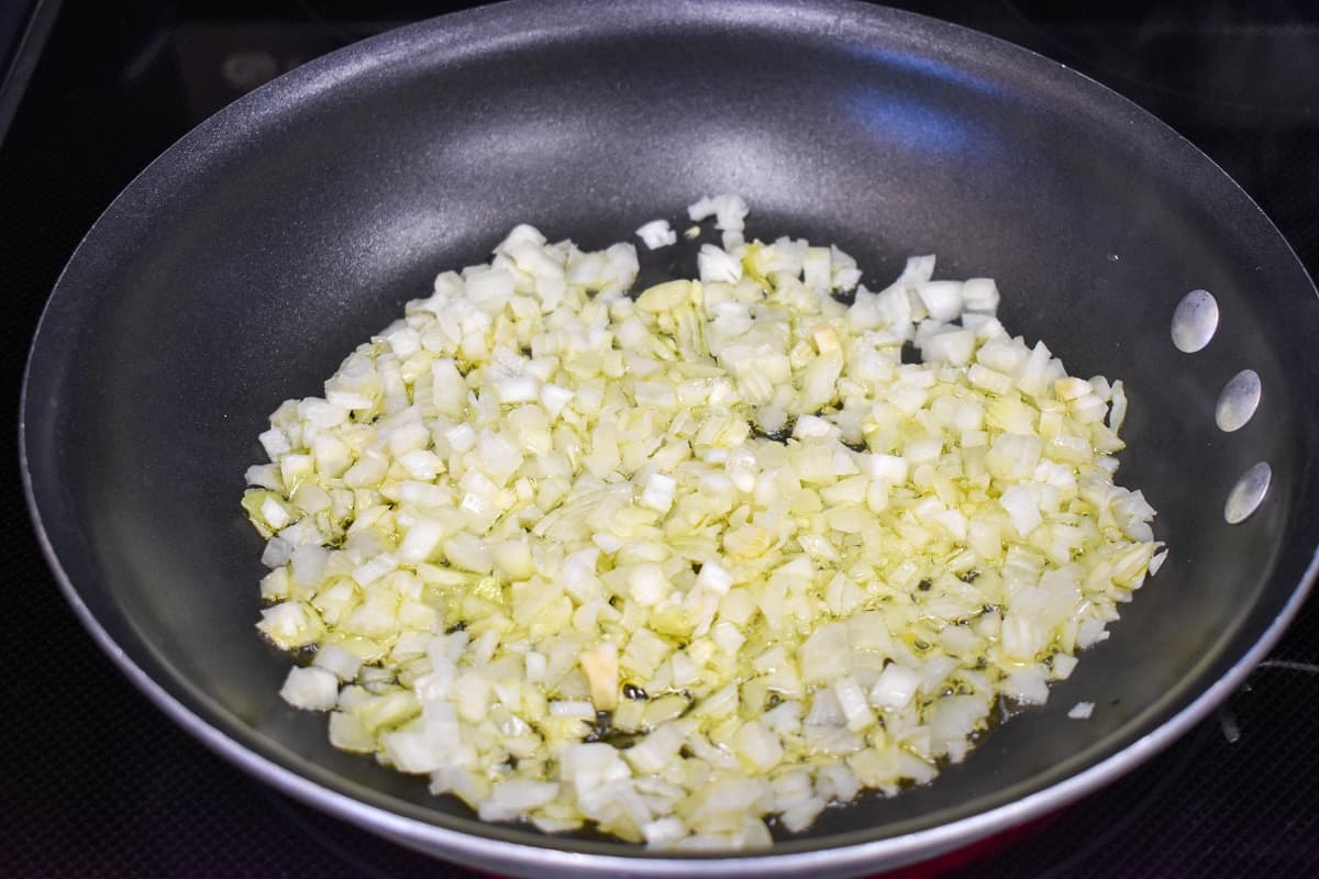 Diced onions cooking in olive oil in a non-stick skillet.