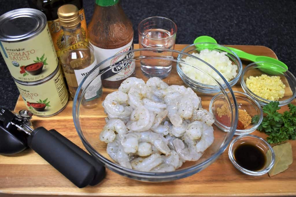 Camarones Enchilados Prep Work, raw shrimp, spices, sauces, diced onions and garlic displayed on a wood board