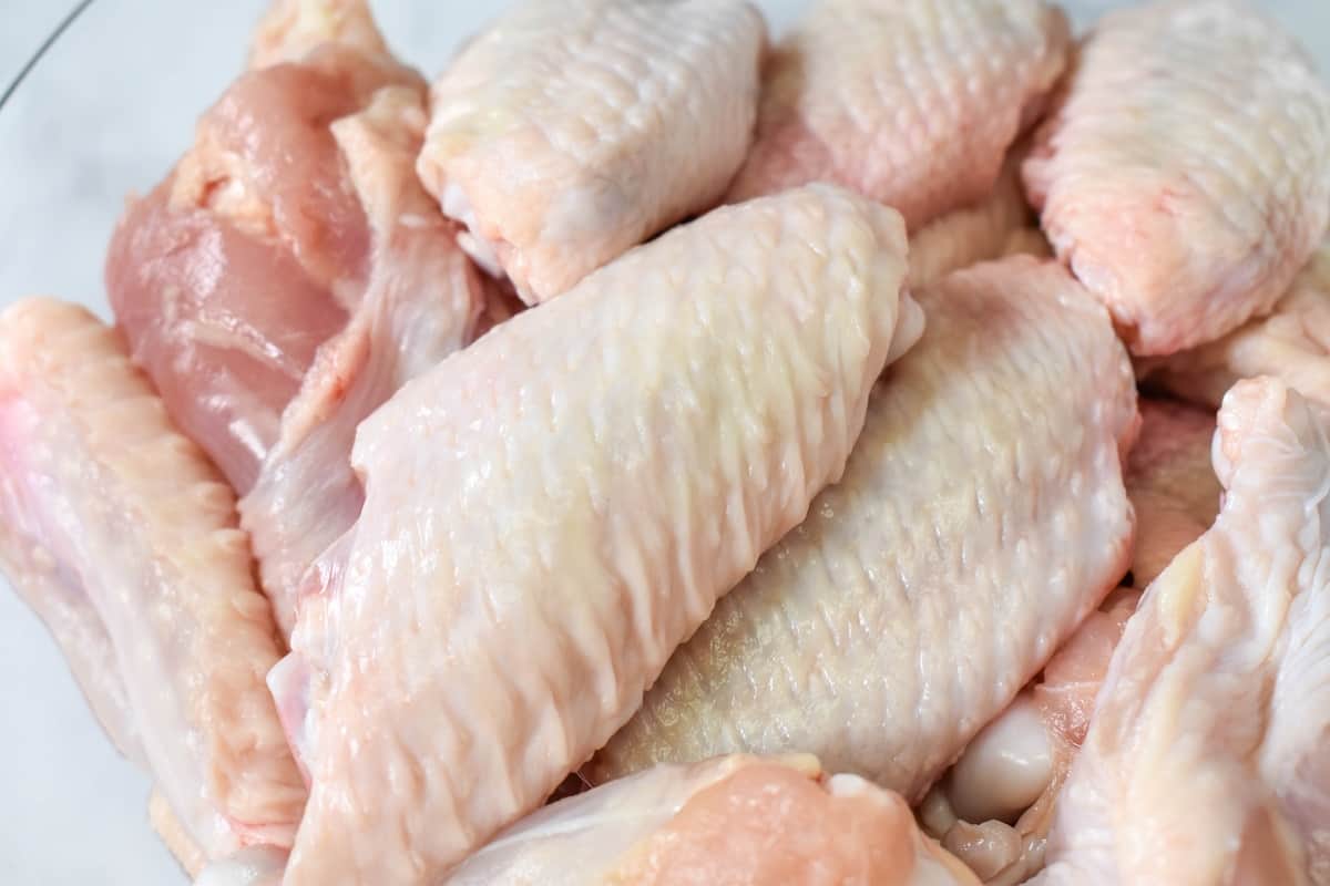 A close up image of raw chicken wings where the flat and drumette are separated.