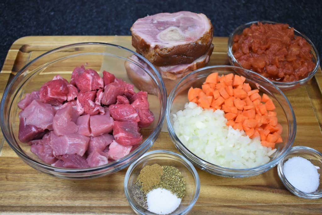 Meat and Aromatics for Ajiaco displayed in glass bowls on a wood cutting board