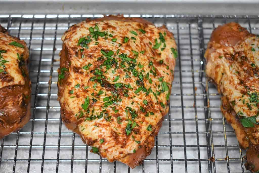 A raw seasoned chicken thigh on a baking sheet.