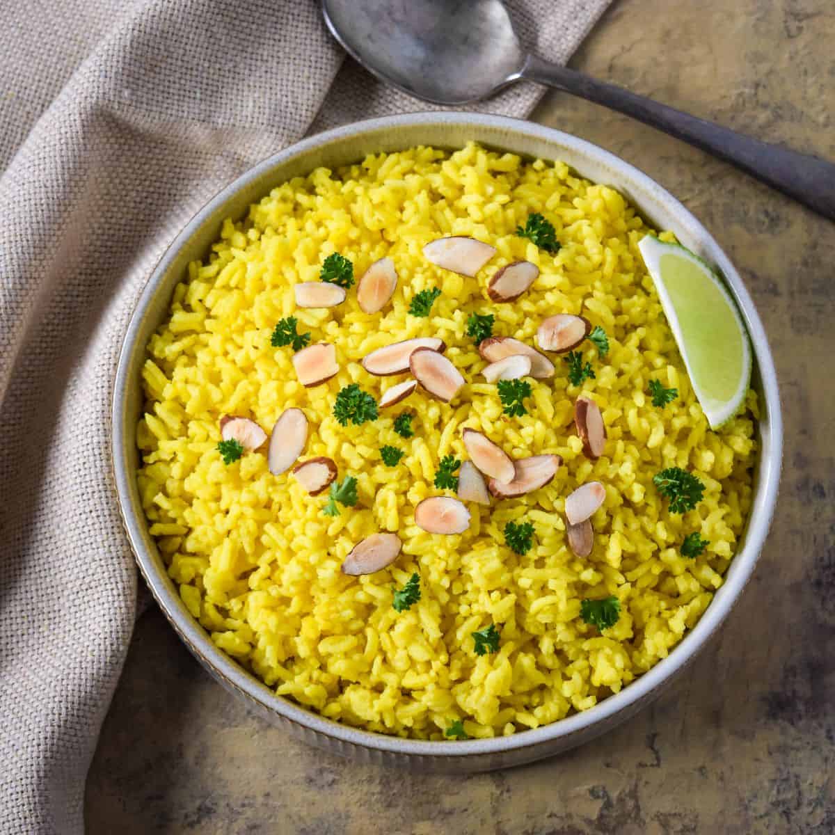 Homemade yellow rice with turmeric topped with sliced toasted almonds and fresh parsley.