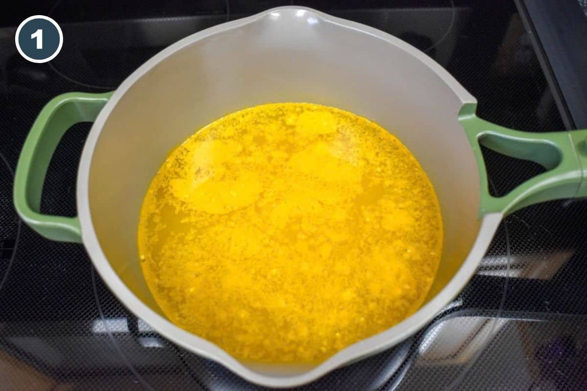 Chicken base, dried onion, and turmeric dissolved in boiling water in a saucepan.