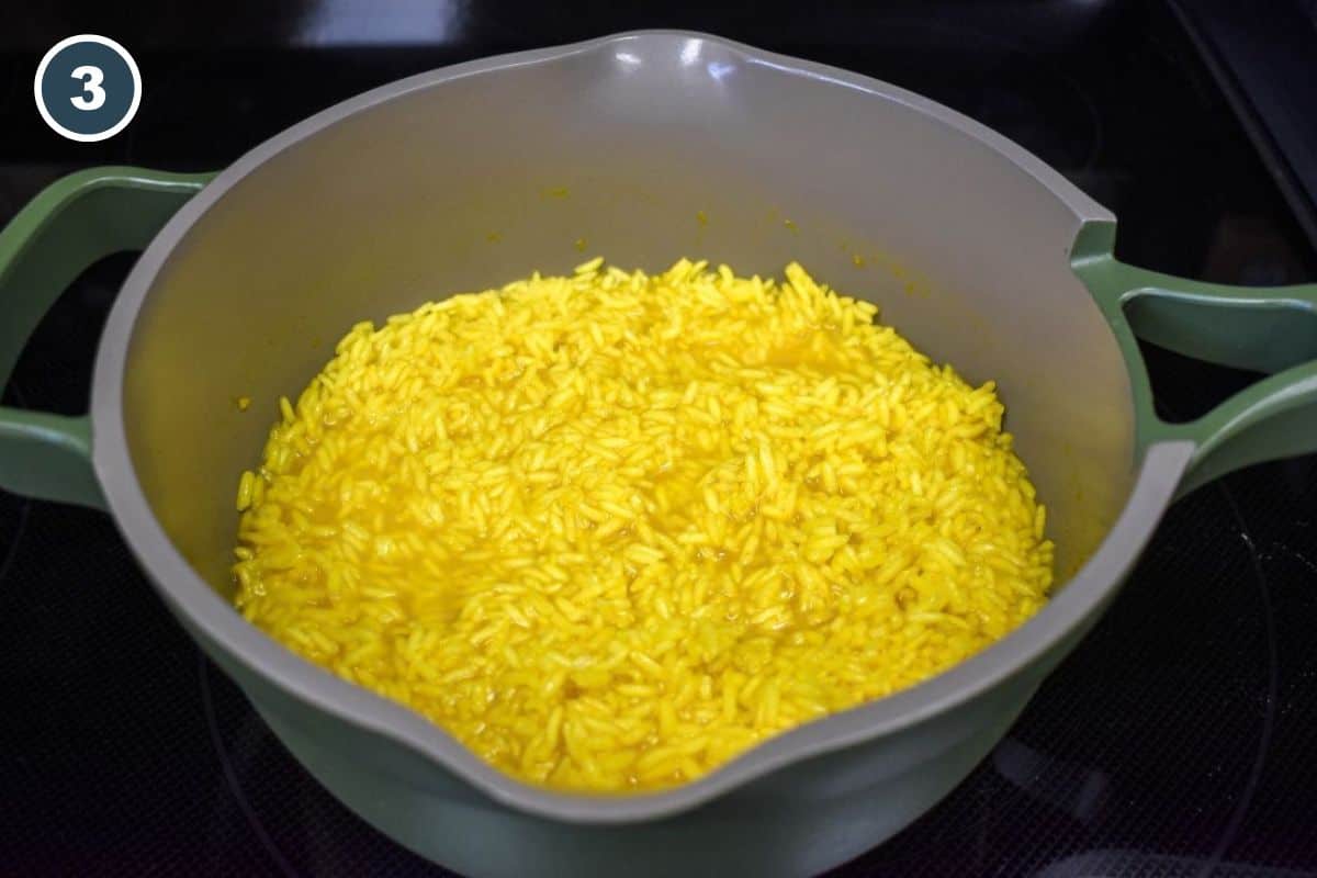 Rice simmering uncovered after most of the cooking liquid has been absorbed.