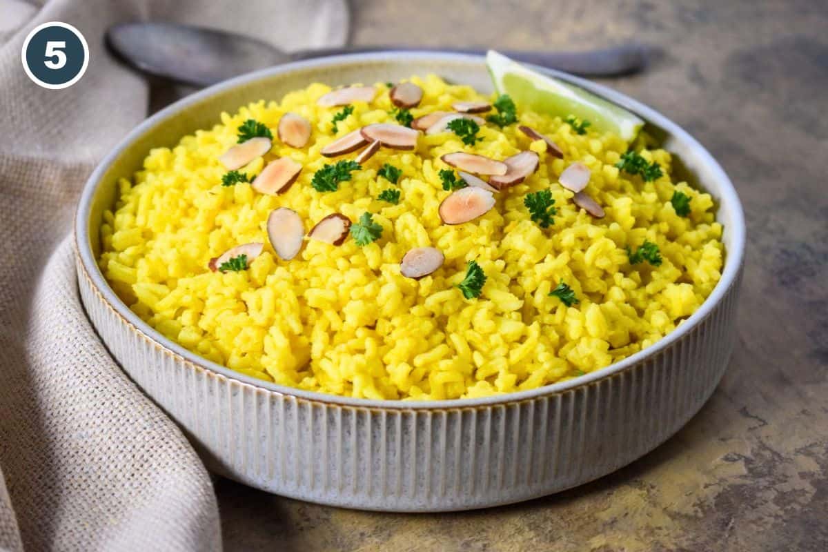 Finished yellow rice topped with toasted sliced almonds and fresh parsley.