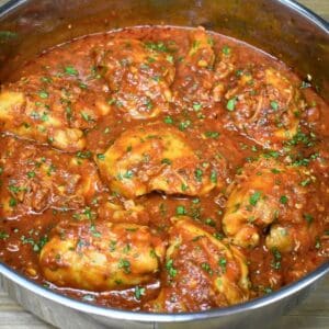 Pollo en salsa, chicken thighs in tomato sauce, in a large skillet.