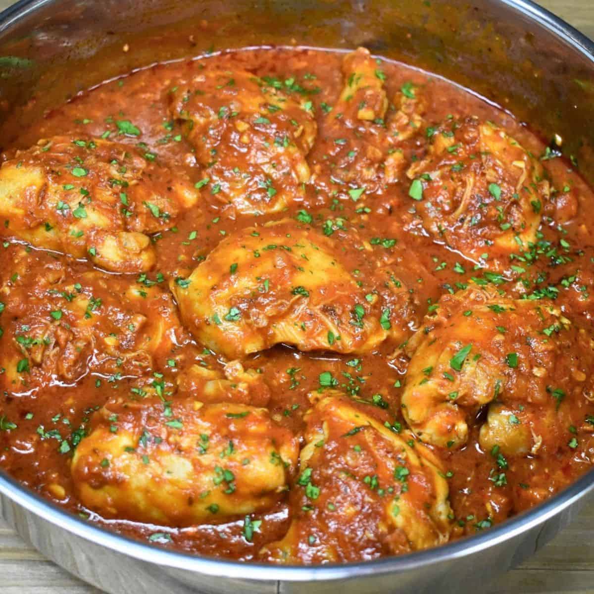 Pollo en salsa, chicken thighs in tomato sauce, in a large skillet.
