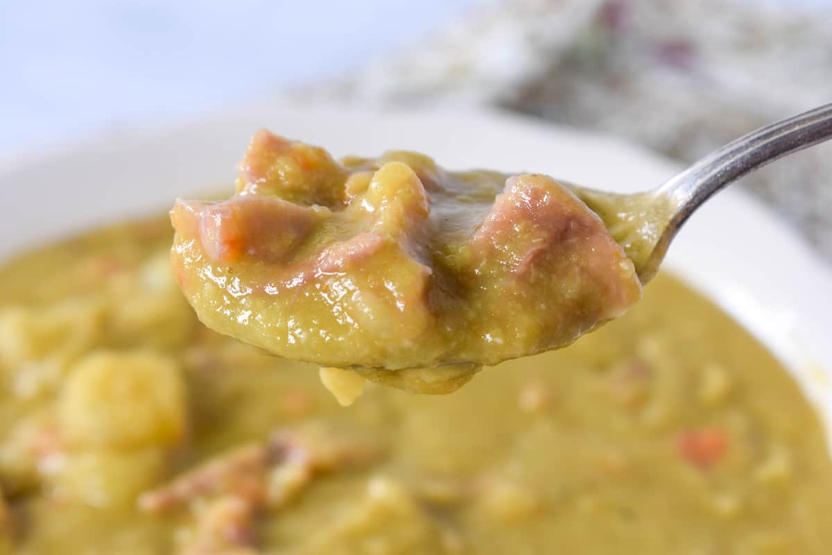 A close up image of a spoon lifting a helping of the split pea soup.