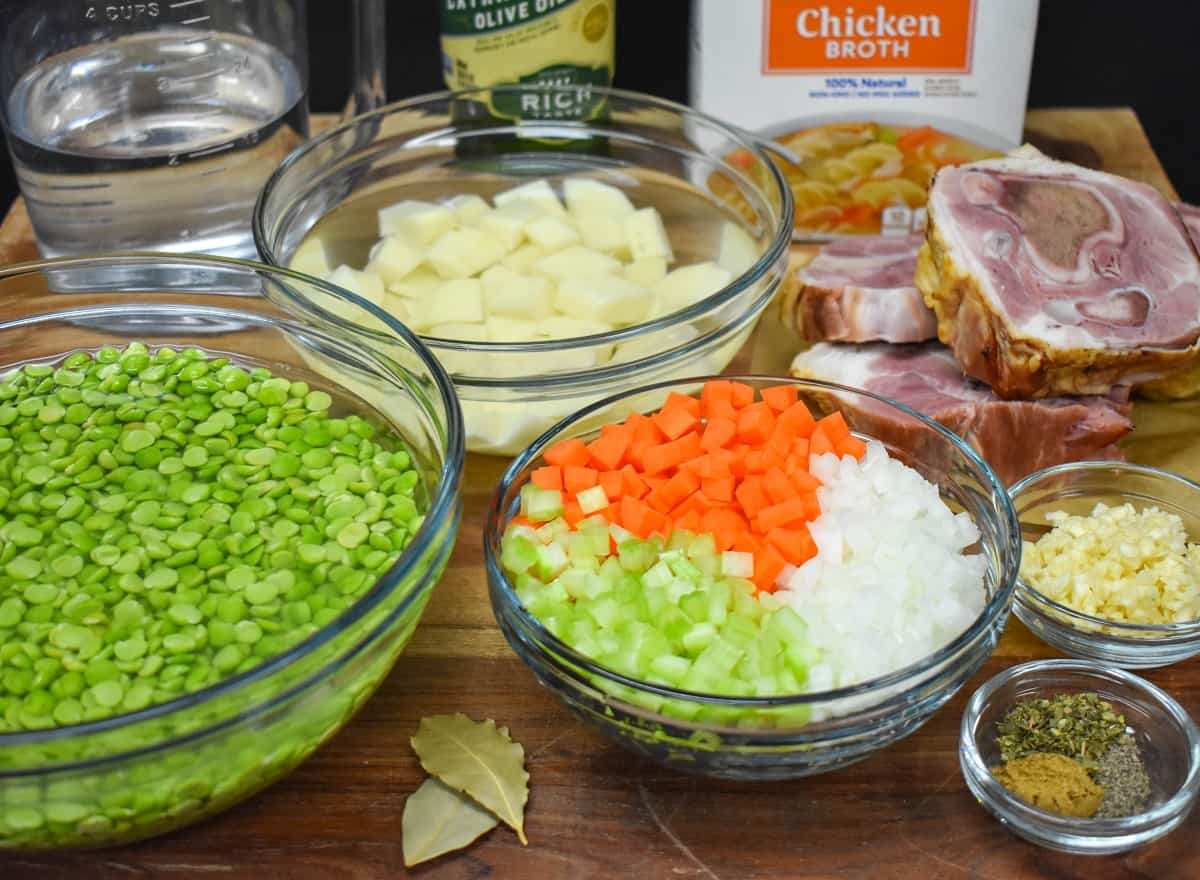 The prepped ingredients for the soup separated in glass bowls and displayed on a wood cutting board.