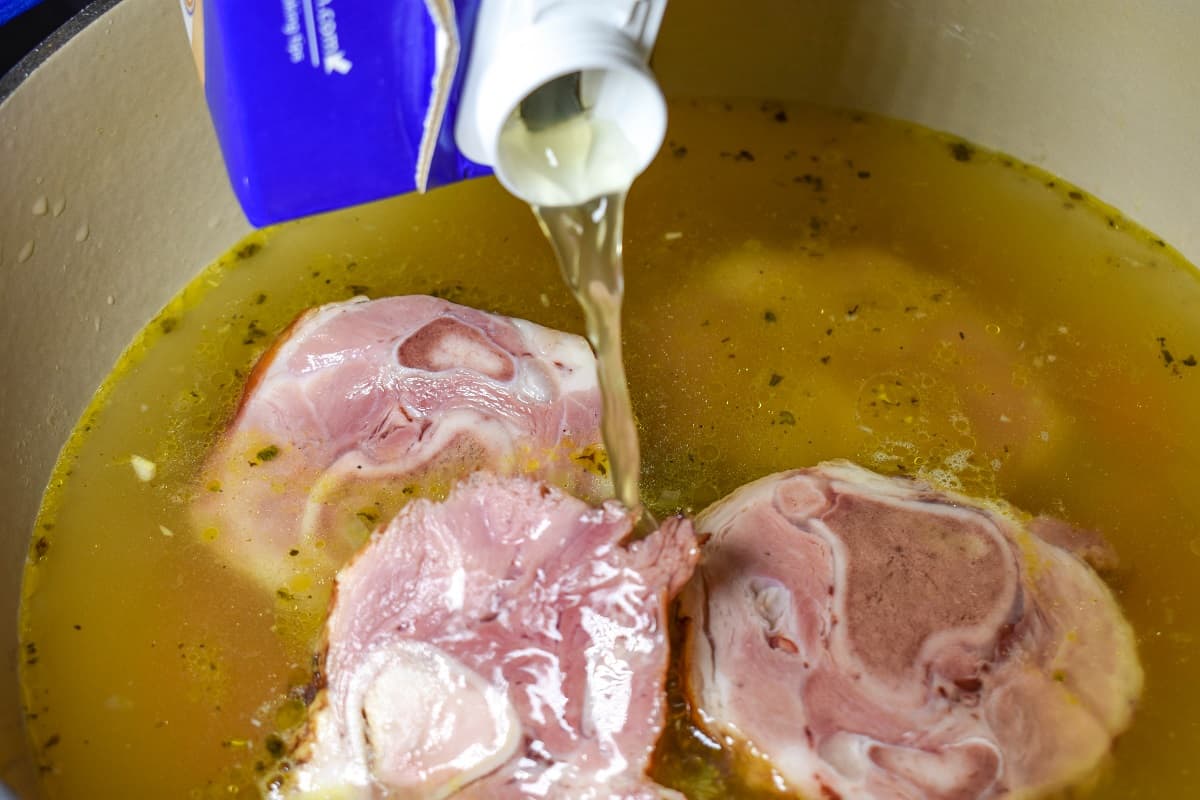 Chicken broth being added to the ingredients in the pot.