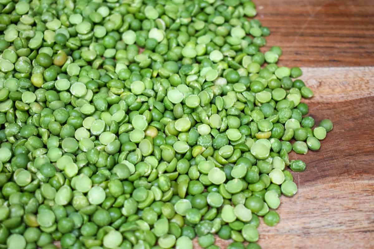 Green split peas displayed on a wood cutting board.