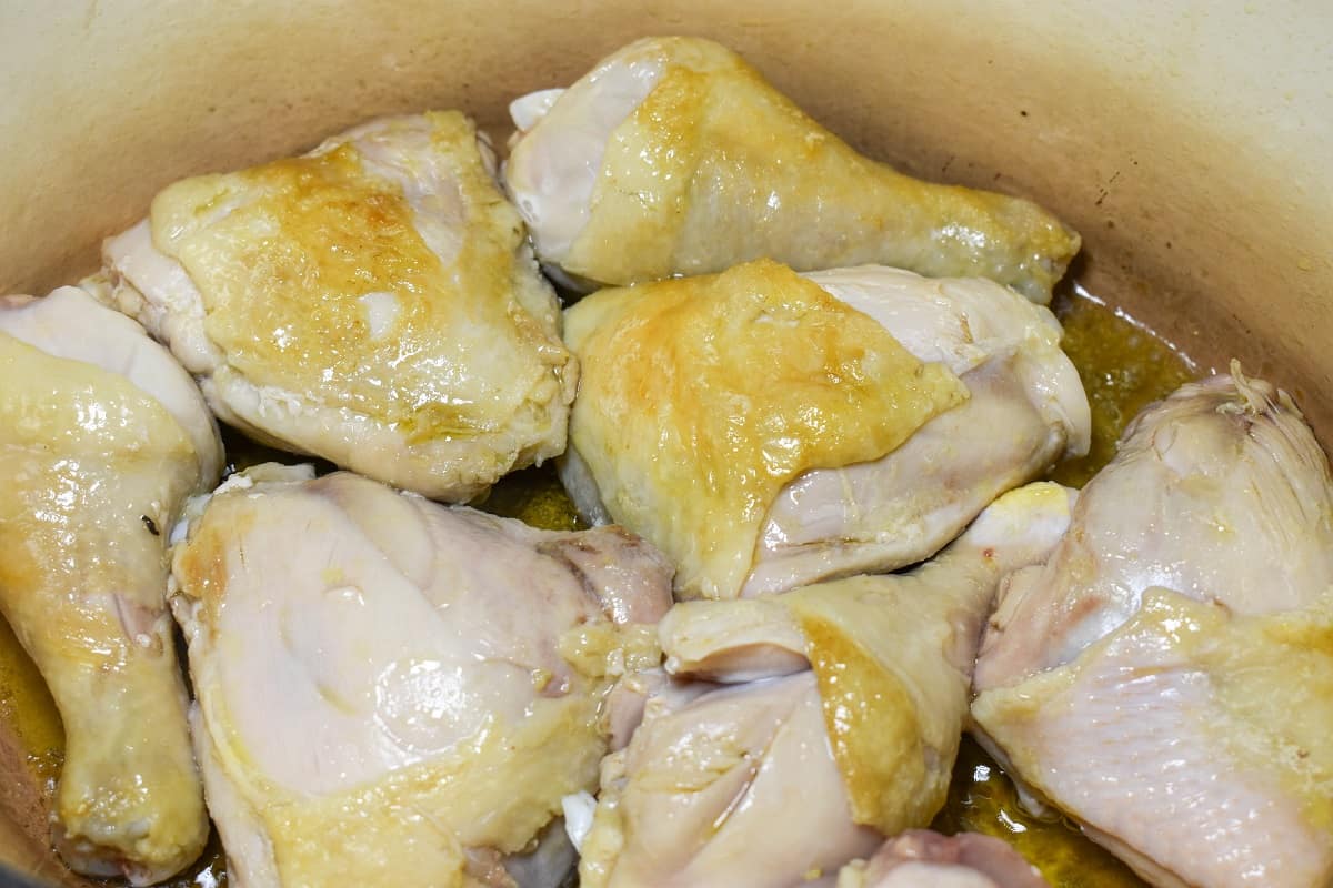 Chicken pieces browning in a large pot.