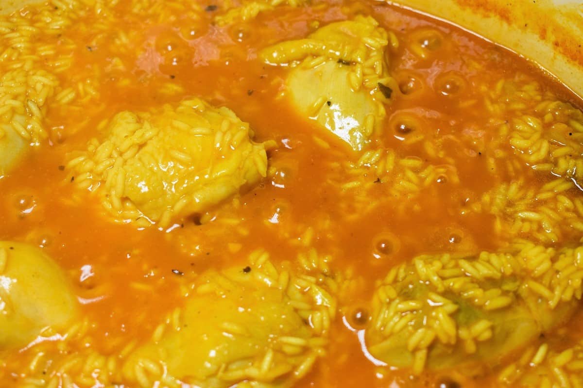 Yellow rice and chicken cooking in a large pot.