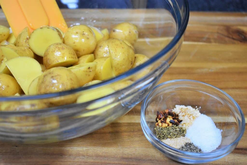 Honey gold potatoes cut in half in a clear glass bowl with a small clear bowl with the seasoning mix next to it.