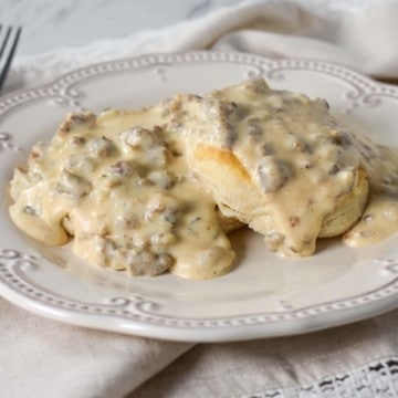 Sausage gravy served over biscuits on a white plate.