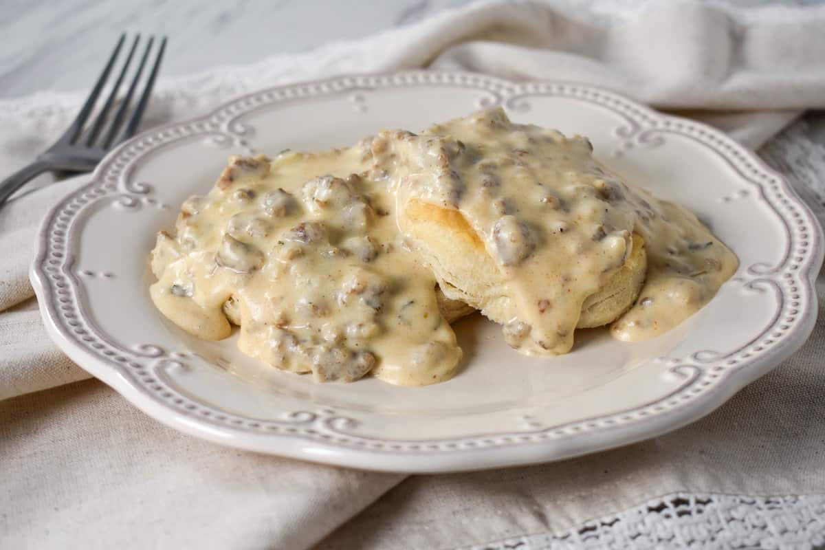 Sausage gravy served over biscuits on a white plate.