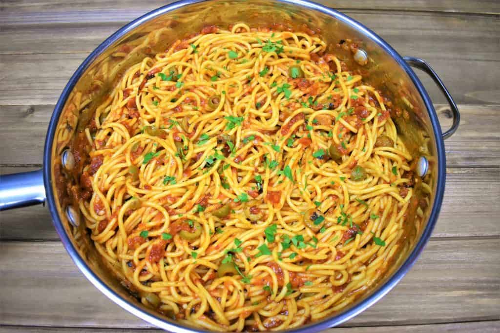 Spaghetti and tomato and olive sauce in a large skillet.