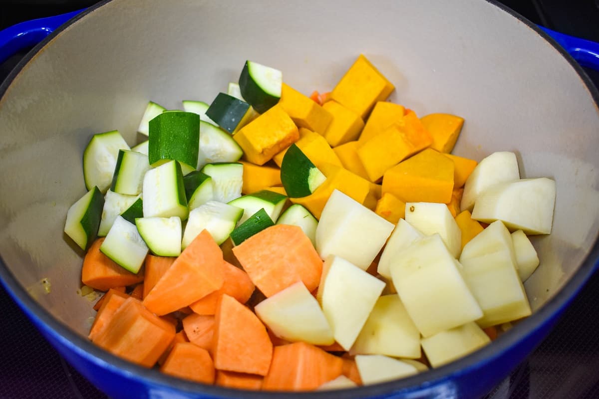 Cut pumpkin, potatoes, sweet potatoes, and zucchini added to a large pot.