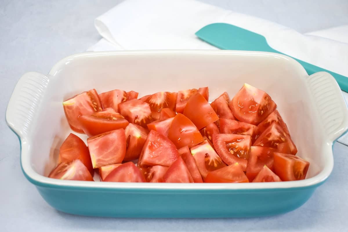 An image of cut tomatoes in a light blue and white baking dish.