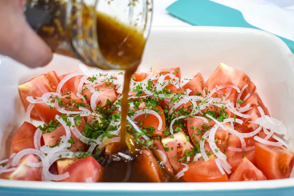 The marinade being poured over the tomatoes.