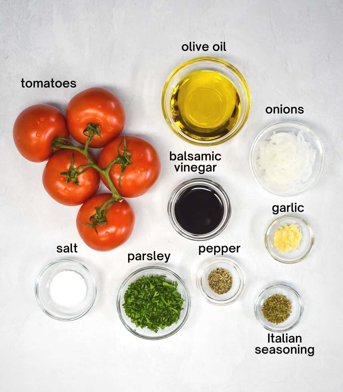 The ingredients for the dish arranged on a white table and labeled in small black letters.