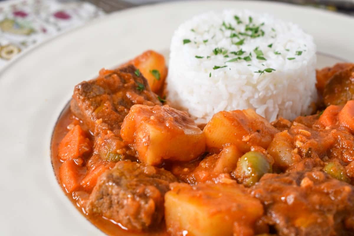 A close-up of the finished dish served with with rice on a white plate.