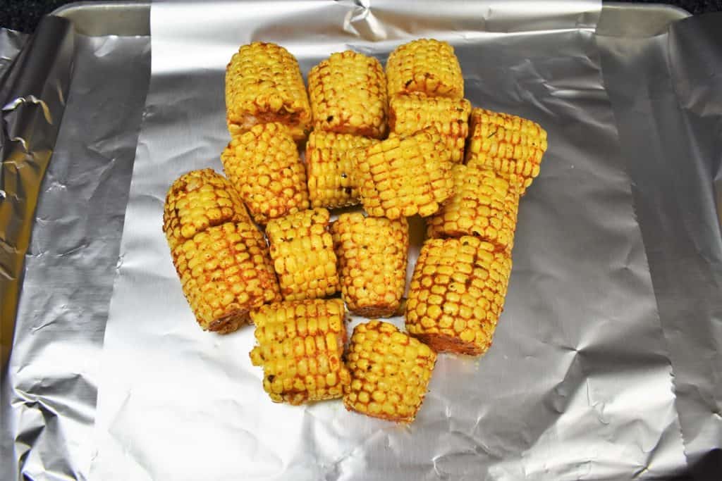 Seasoned, cut corncobs on aluminum foil.
