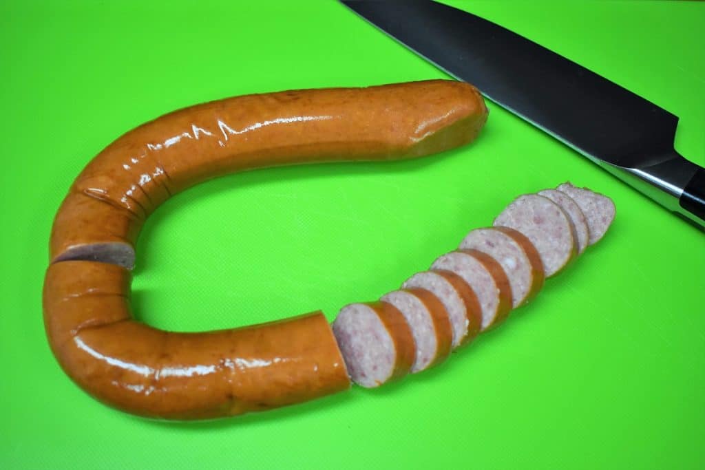 Sausage Polska Kielbasa, one end sliced on a green cutting board