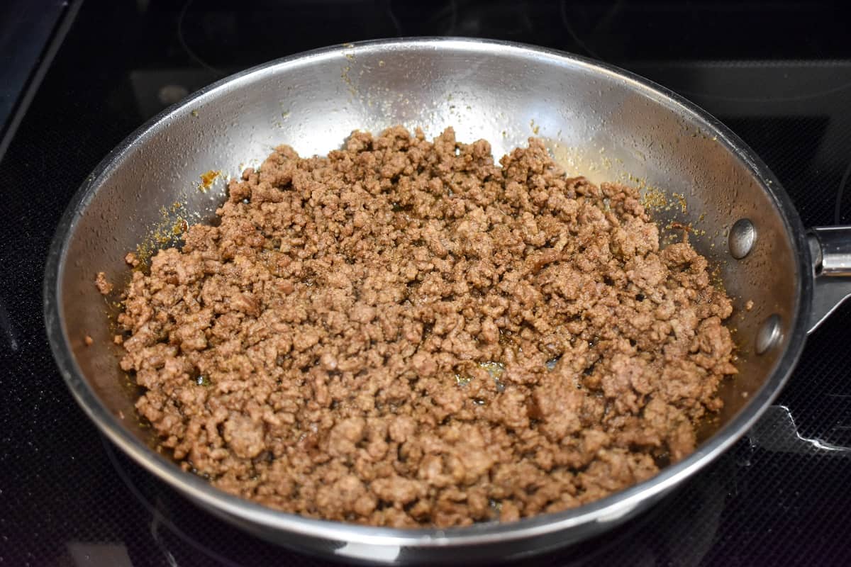 Ground beef in a skillet after draining the oil.