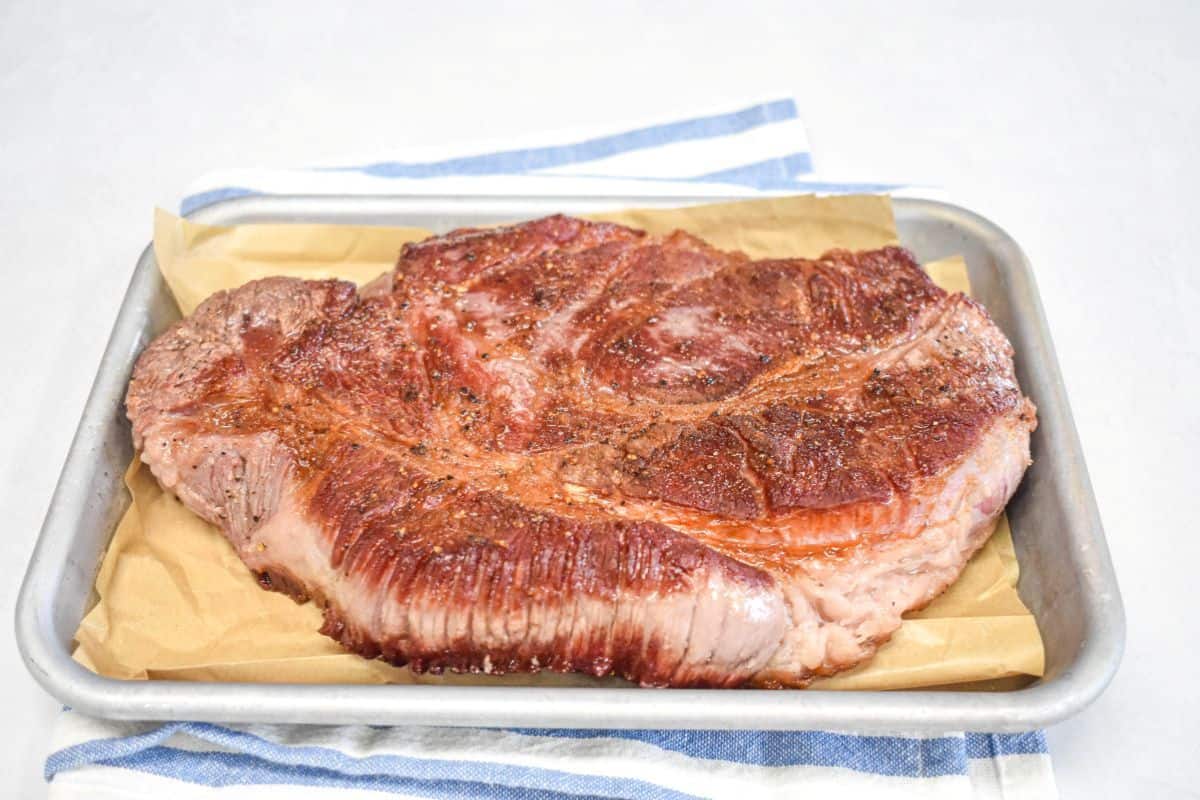 Browned beef chuck roast resting on a pan after searing.