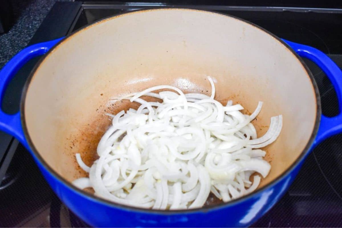 Sliced onions cooking in the Dutch oven after browning the beef.