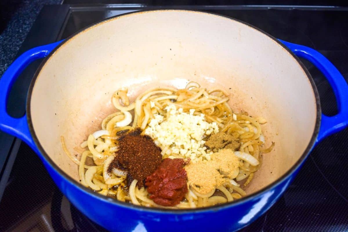 Garlic, tomato paste, chili powder, garlic powder, onion powder, and cumin added to the cooked onions.