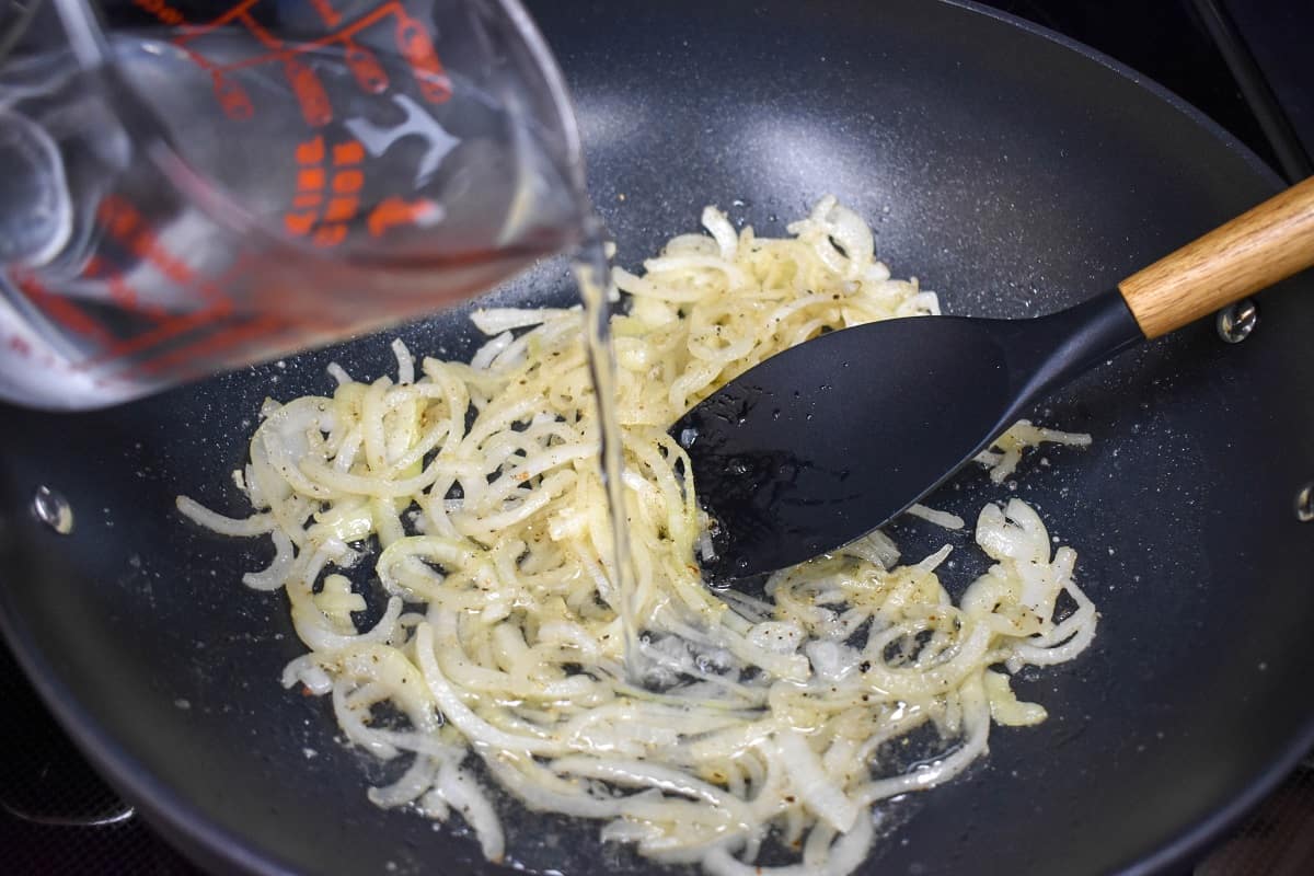 Water being added to the onion mixture in the skillet.