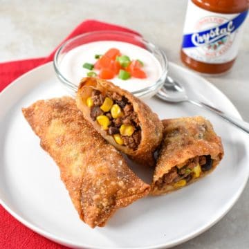 Two southwestern egg rolls on a white plate, one is cut in half.