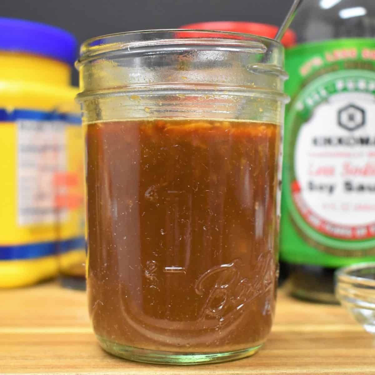 A small jar with the stir fry sauce. The ingredients for the sauce like the soy sauce and cornstarch are in the background.